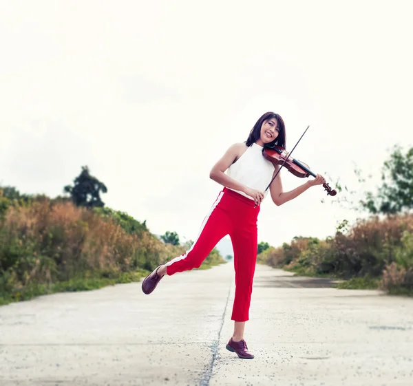 那个拉小提琴的漂亮女人 带着愉快的心情 带着乡村的景色 周围的光线模糊了 — 图库照片