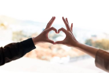 İnsan dokunuşunun parmakları, kalp şekli, işaret ve aşkın sembolü etrafında bulanık bir ışık oluşturuyor.