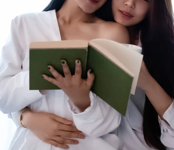 Two beautiful women reading book,doing activity together,closed relationship,portrait of model posing,blurry light around