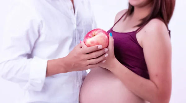 妊娠中の女性と夫の手の選択的な焦点で一緒に赤いリンゴを保持 周りのぼやけた光 — ストック写真