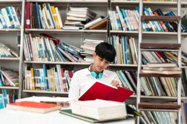 Kütüphanede kitaptan veri arayan genç bir kız.