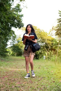 Güzel kadın sırt çantası, boynuna kamera takmak, seyahat notları yazmak, tatilde, zaman arasında yürümek.
