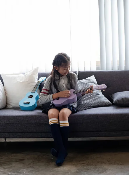 Μικρό Κορίτσι Που Κάθεται Στον Καναπέ Παίζοντας Γιουκαλίλι Χαρούμενη Αίσθηση — Φωτογραφία Αρχείου