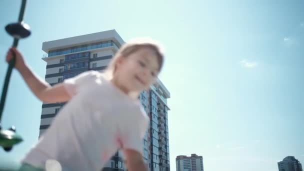 Little girl play on park playground with a carousel. A lonely child is riding a carousel with toy in yard on summer. Pretty child spins on a carousel. Adorable girl has fun at playground. — Stockvideo