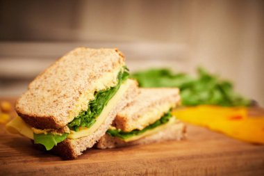 Tahtada ikiye bölünmüş peynirli ve nohutlu sağlıklı roket sandviçi.