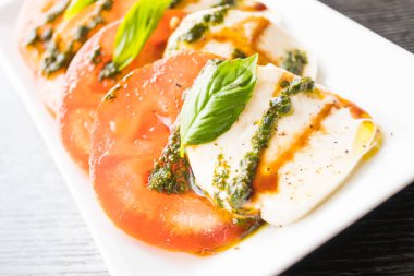 Beyaz tabakta domates ve mozzarella peynirli salata