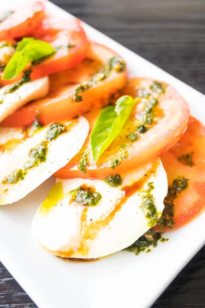 Салат з помідорами та сиром моцарелла в білій тарілці — стокове фото