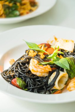 Deniz ürünleri beyaz tabak içinde siyah spagetti