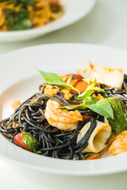 Deniz ürünleri beyaz tabak içinde siyah spagetti