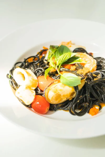 Czarne Spaghetti z owocami morza w biały talerz — Zdjęcie stockowe
