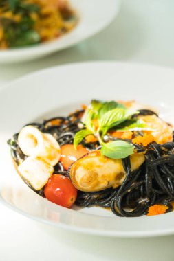 Deniz ürünleri beyaz tabak içinde siyah spagetti