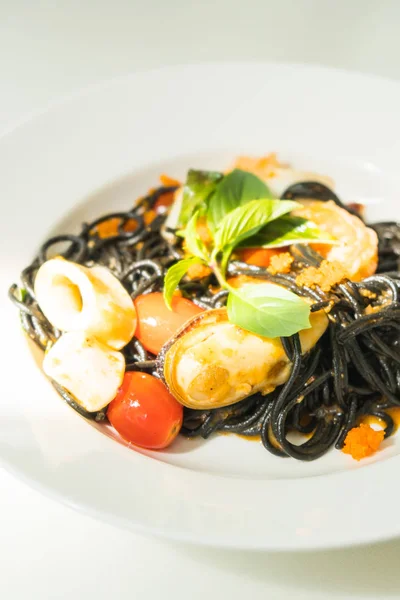 Černé špagety s mořskými plody v bílé desky — Stock fotografie