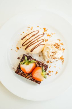Vanilyalı dondurma ile Çikolatalı browni kek üzerinde çilek ile