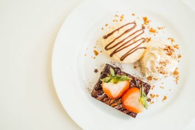 Vanilyalı dondurma ile Çikolatalı browni kek üzerinde çilek ile