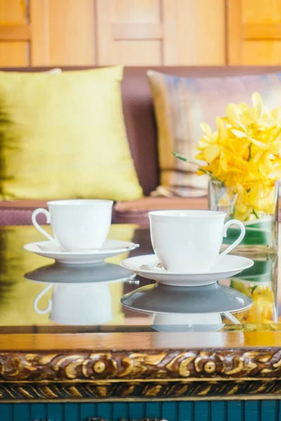 Vazo çiçek ve beyaz kahve fincanı masada ve kanepe yastık