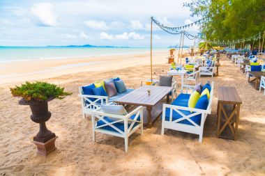 Sandalye ve masa üzerinde plaj ve deniz mavi gökyüzü ile yemek