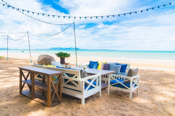 Sandalye ve masa üzerinde plaj ve deniz mavi gökyüzü ile yemek