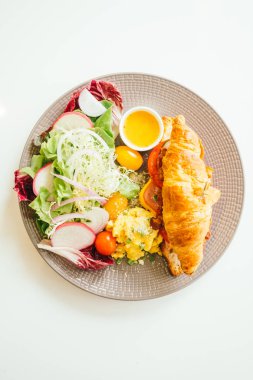 Sahanda yumurta ve sebze ve kruvasan sandviç gevrek domuz pastırması jambon peynir içinde - renk filtresi işleme ile kahvaltı tabağı