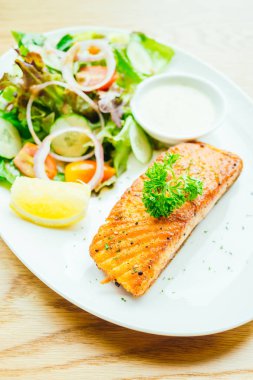 Beyaz tabakta sebze salatası ve somon eti fileto.