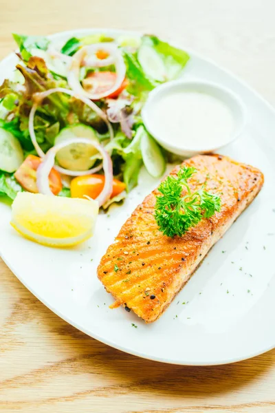 Beyaz tabakta sebze salatası ve somon eti fileto.