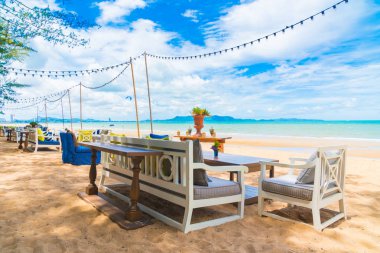 Sandalye ve masa üzerinde plaj ve deniz mavi gökyüzü ile yemek