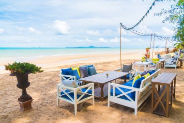 Sandalye ve masa üzerinde plaj ve deniz mavi gökyüzü ile yemek