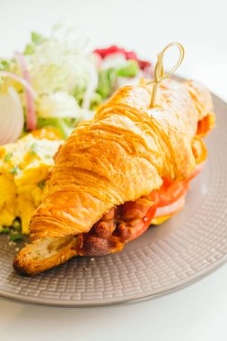 Sahanda yumurta ve sebze ve kruvasan sandviç gevrek domuz pastırması jambon peynir içinde - renk filtresi işleme ile kahvaltı tabağı