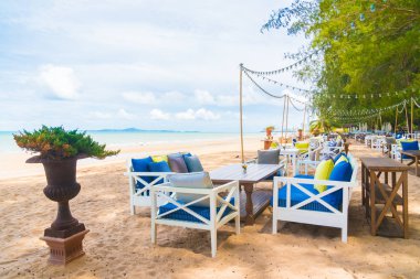 Sandalye ve masa üzerinde plaj ve deniz mavi gökyüzü ile yemek