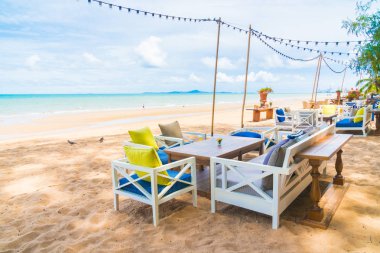 Sandalye ve masa üzerinde plaj ve deniz mavi gökyüzü ile yemek