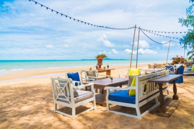 Sandalye ve masa üzerinde plaj ve deniz mavi gökyüzü ile yemek