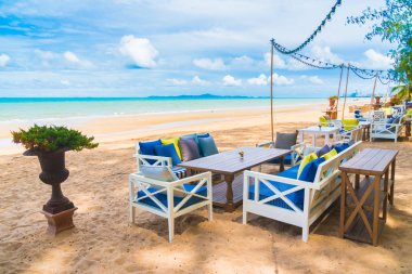 Sandalye ve masa üzerinde plaj ve deniz mavi gökyüzü ile yemek