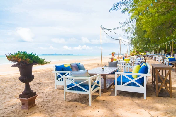 Sandalye ve masa üzerinde plaj ve deniz mavi gökyüzü ile yemek