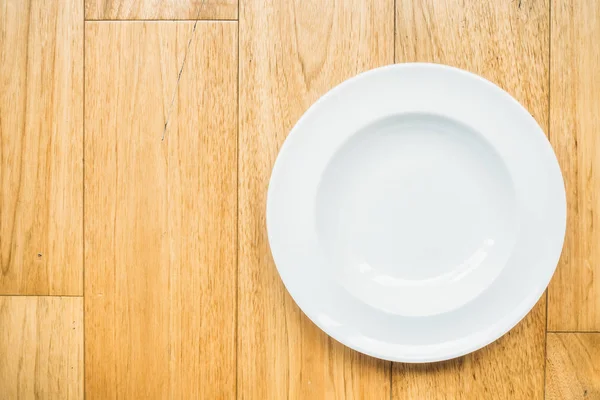 Пустая белая тарелка на деревянном фоне — стоковое фото
