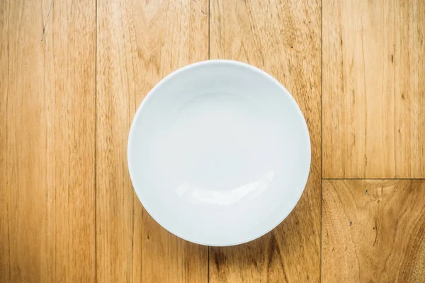 Пустая белая тарелка на деревянном фоне — стоковое фото