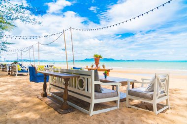 Sandalye ve masa üzerinde plaj ve deniz mavi gökyüzü ile yemek