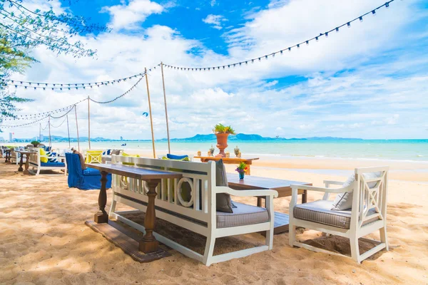 Sandalye ve masa üzerinde plaj ve deniz mavi gökyüzü ile yemek