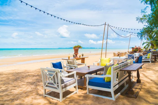 Sandalye ve masa üzerinde plaj ve deniz mavi gökyüzü ile yemek