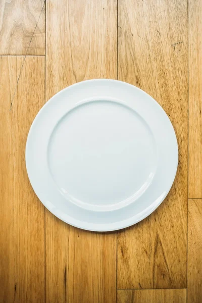 Empty white plate on wooden background — Stock Photo, Image