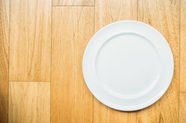 Ahşap zemin üzerinde boş beyaz tabak