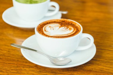 ahşap masa üzerinde beyaz fincan sıcak çikolatalı latte