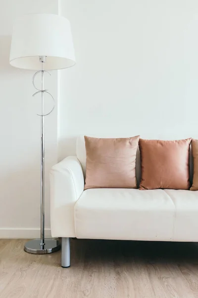 Bequemes Kissen auf weißem Sofa mit heller Lampe — Stockfoto