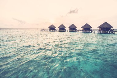 Güzel tropikal gün batımı ile su bungalov otel Resort - Maldivler ada üzerinde Vintage filtre ve alttan yukarıya ittirmek yukarıya renk işleme