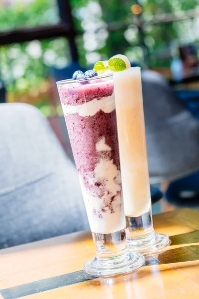 健康食品と飲料スタイル ヨーグルト ガラス テーブルにアイス ブルーベリー スムージー — ストック写真