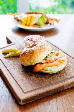 Simit ekmek ile füme somon et ve sebze ahşap kesme tahtası üzerinde