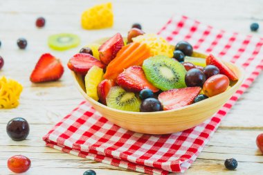 Kivi çilek üzüm ve diğer ahşap masa - filtre işleme üzerinde kase ile karışık ve çeşitli meyve