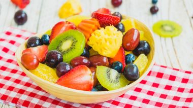 Kivi çilek üzüm ve diğer ahşap masa - filtre işleme üzerinde kase ile karışık ve çeşitli meyve