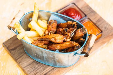 Kızarmış tavuk kanadı soslu patates kızartması ile