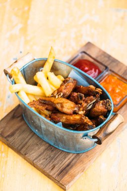 Kızarmış tavuk kanadı soslu patates kızartması ile