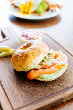 Simit ekmek ile füme somon et ve sebze ahşap kesme tahtası üzerinde