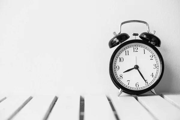 Black clock on table with copy space — Stock Photo, Image